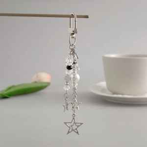 Detail of silver star and cross charms with pearlescent beads on a metal keychain
