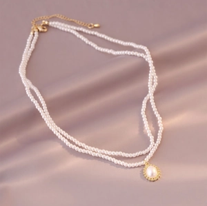 Close-up of double-layer white pearl choker with a gold-rimmed pearl pendant on silk