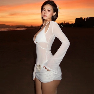 Détail de la robe de plage en maille blanche avec paillettes et volants au coucher du soleil