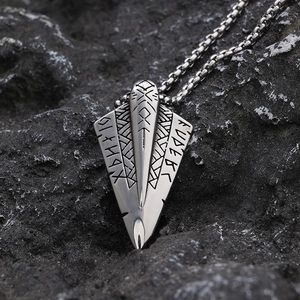 Vintage stainless steel Viking spearhead pendant with runes on rugged stone background