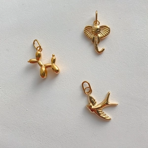Detailed view of 14K gold plated charms featuring a balloon dog, elephant, and swallow bird