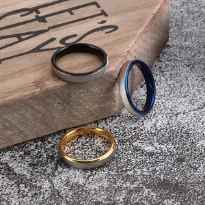 Brushed stainless steel rings with black blue and gold inner bands on wooden block