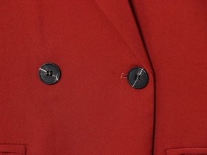 Detailed close-up of double-breasted buttons and red matte fabric on a tailored blazer