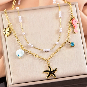 Macro detail of gold layered necklace with starfish and seahorse pendants on a silk box