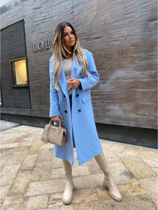 Detail of light blue double-breasted wool coat featuring classic notched lapels and flap pockets