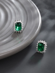 Macro view of emerald-cut green stone earrings with cubic zirconia halo setting