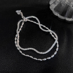 Double-layer silver bracelet with olive beads and shimmering snake chain on black background