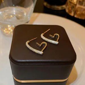 Gold plated heart earrings with zircon stones on premium dark brown leather background