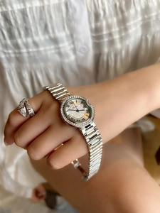 Close-up of elegant silver steel watch with diamond-set bezel worn on a female wrist