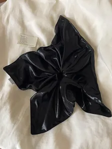 Close-up of oversized black satin scrunchie with glossy finish and elegant folds