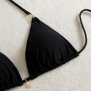 Detail of black bikini top featuring gold starfish pendant and metallic ring accents