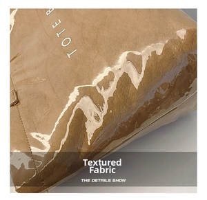 Detailed macro view of crinkled brown fabric with glossy waterproof coating on a tote bag