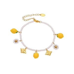 Fresh pearl bracelet with resin lemon, daisy and bee charms on a white background