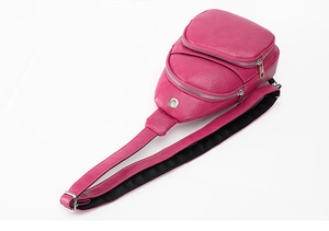 Detail view of rose red PU leather chest bag with zipper pockets and headphone port hole