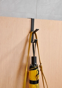 Detail of a black double-headed door hook holding a yellow bag and umbrella for storage