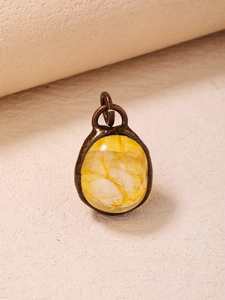 Detail of yellow oval crystal pendant with natural cracks in bronze metal frame