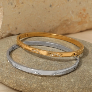 Elegant gold and silver wave bangles with sparkling zircons on natural stone