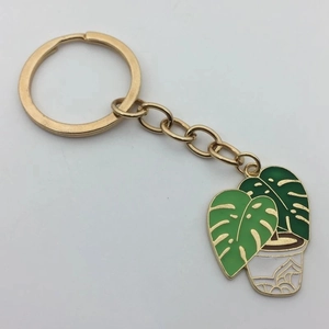 Golden keychain featuring a monstera leaf succulent plant pendant with green enamel