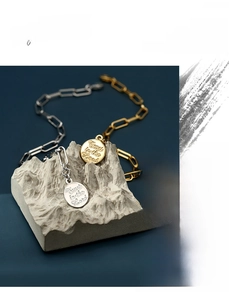Detail of gold and silver paperclip chain bracelets with Trust in the Lord coin pendants