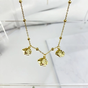 Detail of gold-plated necklace featuring three tropical fish pendants on beaded chain