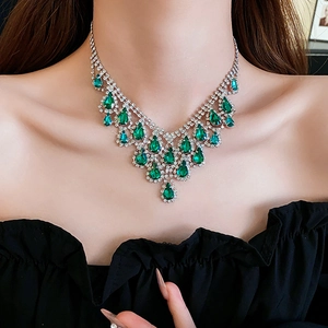 Detailed view of layered silver necklace with green water drop crystals on model