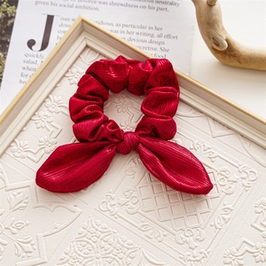 Detail of red satin bunny ear hair scrunchie placed on an open magazine background