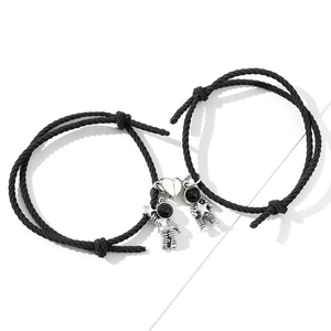 Detail of woven astronaut couple bracelets with magnetic heart charm and black cord