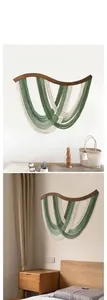 Détail de décoration murale bohème avec cadre en bois courbé et glands en coton bicolore