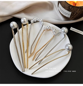 Close-up of elegant U-shaped hair pins with white pearls in gold and silver finish