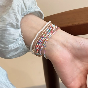 Close-up of Bohemian layered colorful beaded bracelet set worn on a female wrist