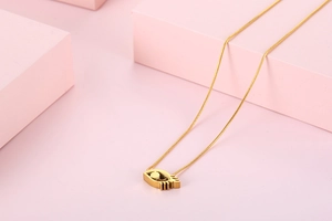 Close-up of golden evil eye pendant necklace on pink geometric display stands