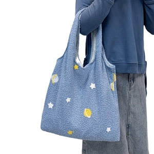 Blue lamb wool tote bag with star and planet embroidery shown on a model side view