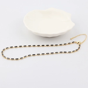 Detail view of a gold-tone necklace featuring rectangular black zircon stones and lobster clasp