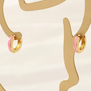 Detail of 18K gold-plated hoop earrings with vibrant pink enamel inlay on display
