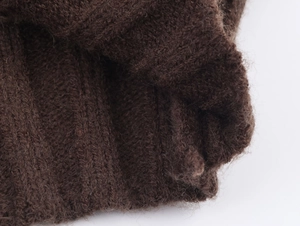 Close-up of vintage brown knit fabric showing soft wool texture and intricate cable pattern