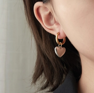 Close-up of heart charm hoop earring in two-tone gold and silver on a female model