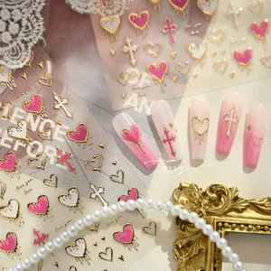 Detail of pink and white gradient nails with gold heart and cross nail stickers