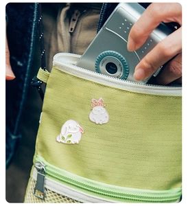 Cute white bunny enamel pins set on green fabric bag with creative cartoon rabbit design