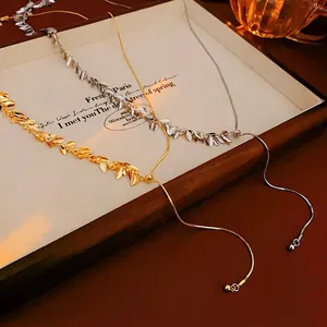 Adjustable leaf tassel necklace in gold and silver finish on a vintage wooden tray