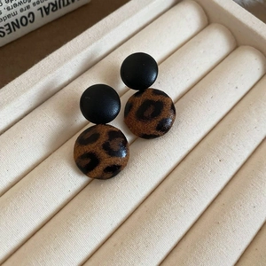Retro leopard print and black leather round stud earrings for women on a beige tray