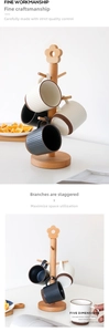 Detail of beech wood tree cup rack with floral top and ribbed ceramic mugs on a table