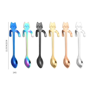 Macro detail of six colorful cat-shaped stainless steel coffee spoons hanging on cup rim