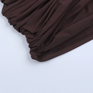 Detailed close-up of dark brown knitted fabric featuring elegant pleated texture and stitching