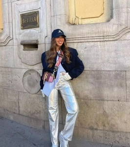 Street style shot of metallic silver straight-leg pants paired with a dark blue jacket