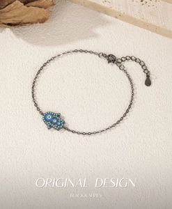 Macro detail of S925 silver Hamsa hand bracelet with blue evil eyes in black gunmetal finish