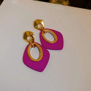 Détails macro des boucles d'oreilles géométriques violet rose avec accents dorés