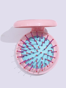 Close-up of pink foldable hairbrush with blue air cushion and multi-colored bristles