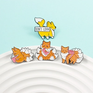 Close-up of cute cartoon fox enamel pins with reading and heart bag motifs on white tray