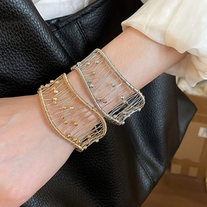 Detailed macro view of gold and silver woven wire cuff bracelets with metallic beads