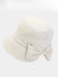 Detail of beige bucket hat featuring twill texture and large bow with golden buckle